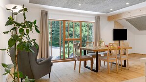 Un comedor con mesa y sillas, una planta y un televisor en la pared.