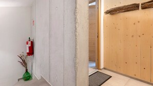 Un pasillo con extintor, puerta de madera y una planta pequeña.