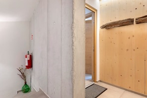 Un corridoio con un estintore, una porta in legno e una piccola pianta.