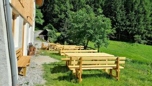 Un bâtiment à l’extérieur en bois, doté d’une terrasse et situé au pied d’une colline boisée.