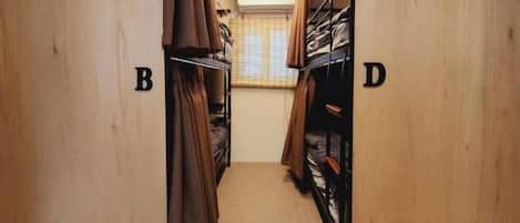 Un pasillo con paredes de madera, secciones identificadas con las letras A, B, C y D, que conduce a una habitación con ventana y puerta.