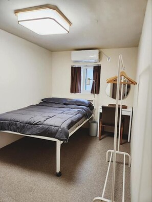 Una habitación compacta con cama, escritorio, sillón colgante y ventana con cortinas.