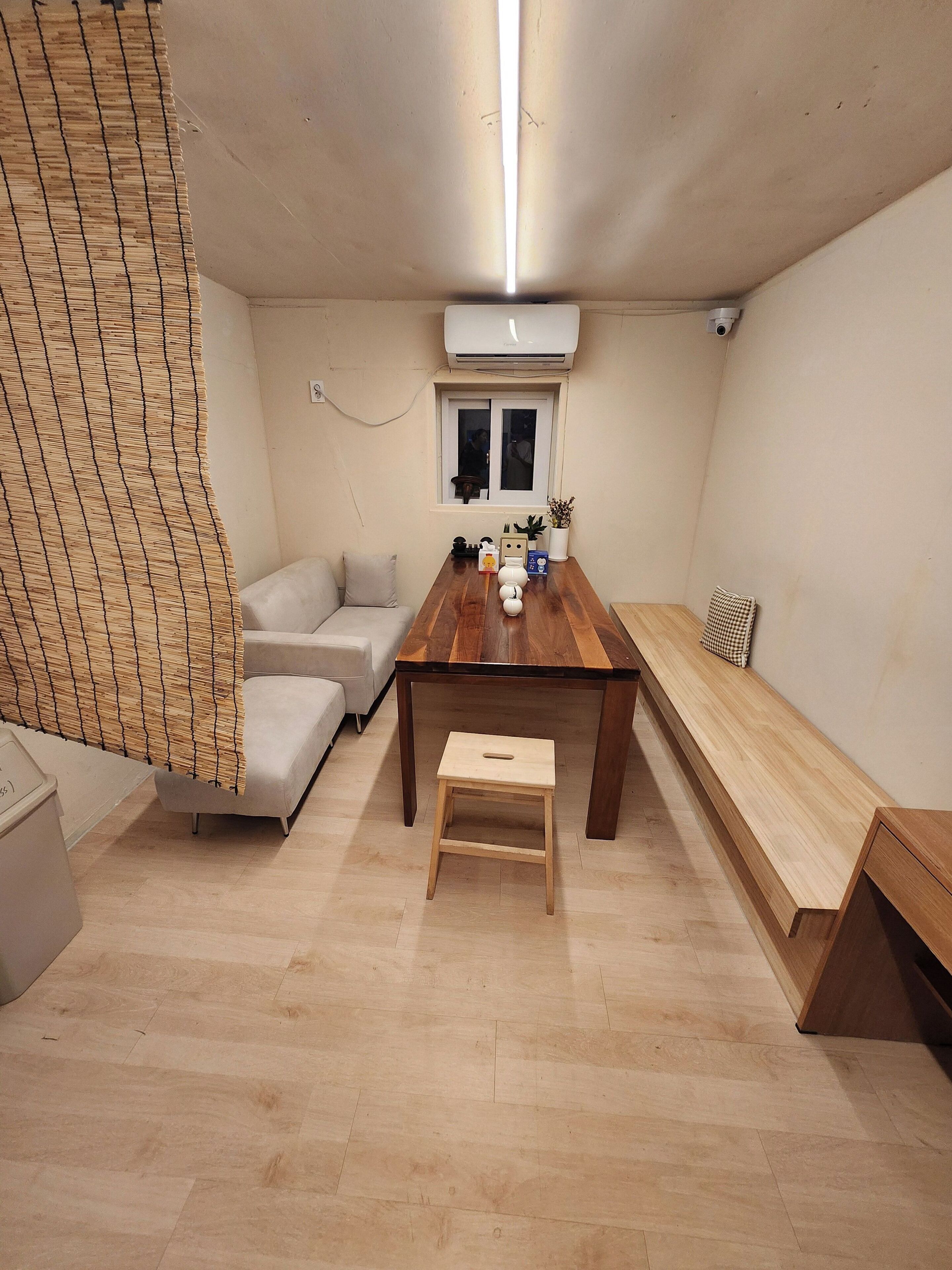 A room with a wooden dining table, a sofa, a bench, and a small stool.