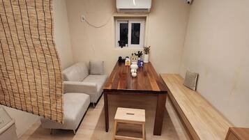 A room with a wooden dining table, a sofa, a bench, and a small stool.