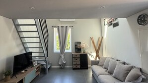 Un salon moderne avec un téléviseur à écran plat, un canapé, un escalier et une fenêtre avec des rideaux.