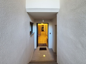 A narrow hallway with a wooden floor leading to a door at the end.