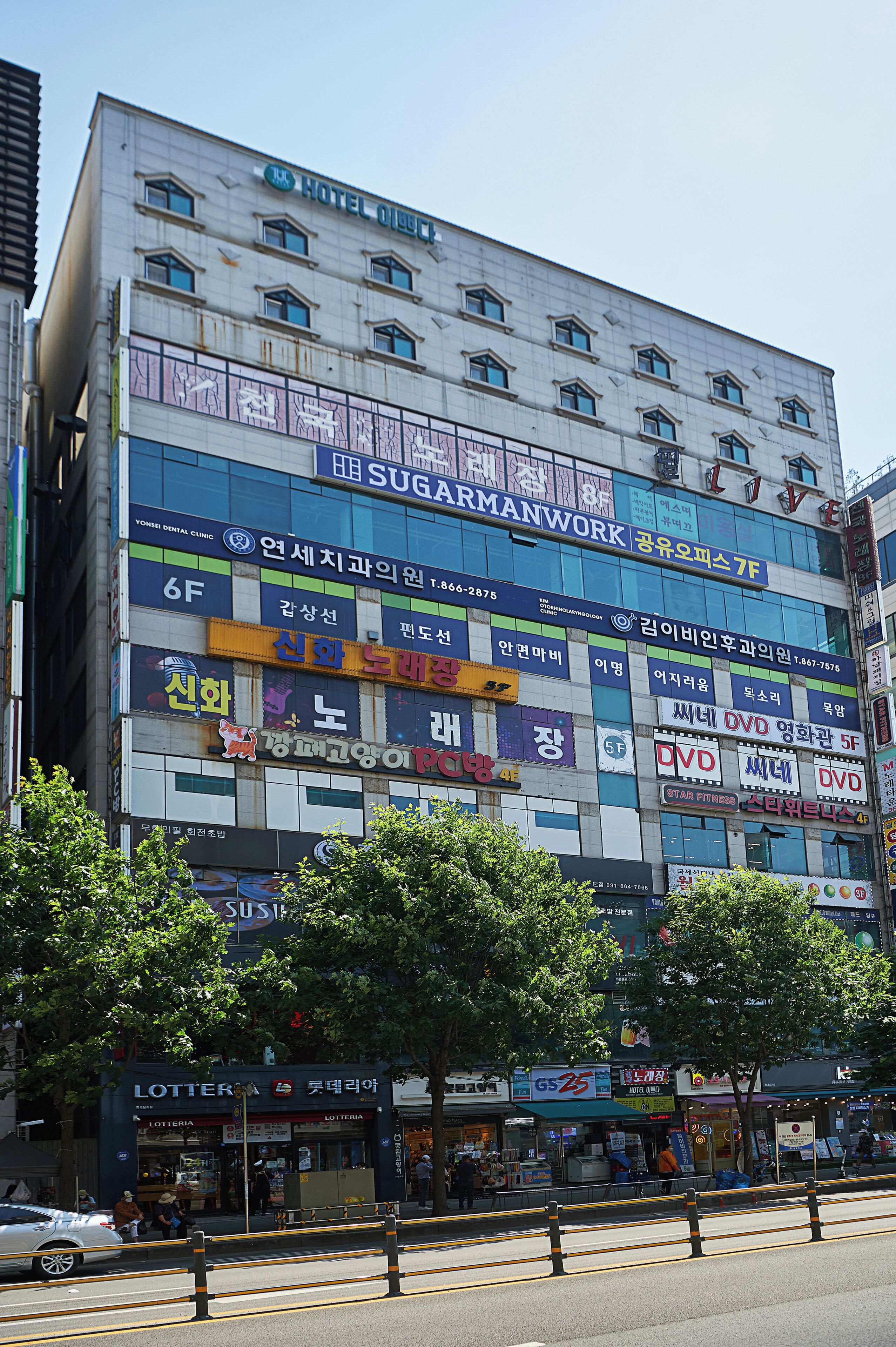 Un edificio de varios pisos con diferentes espacios comerciales, como una clínica dental, una tienda de DVD y una lotería.