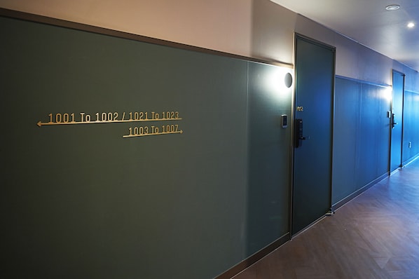 A hallway with doors labeled with room numbers and a light fixture above one door.