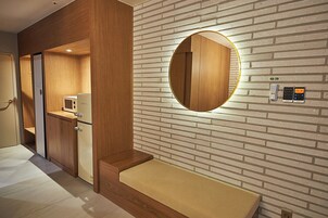 Un baño moderno con tocador de madera, espejo redondo y lavamanos integrado.