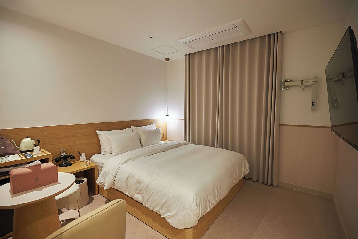 A hotel room with a bed, bedside table, lamp, and a mirror.