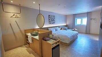 A hotel room with a wooden desk, a bed, a window, and a wall-mounted artwork.