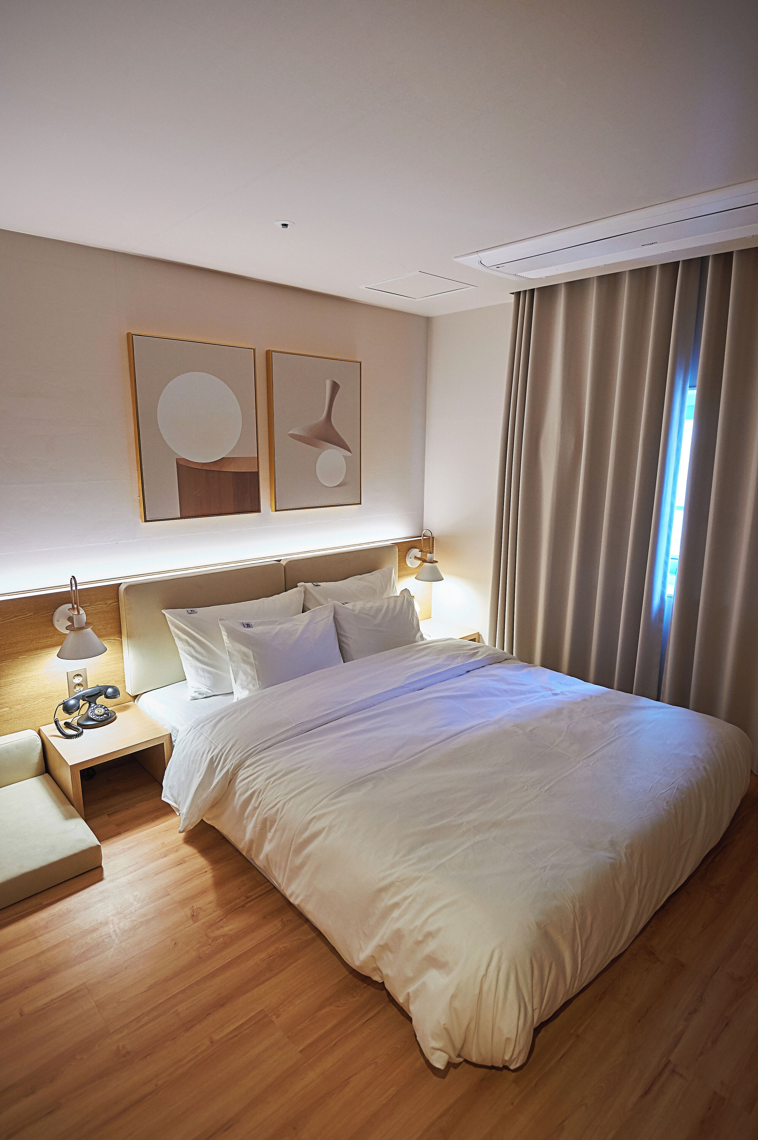 Ein Hotelzimmer mit einem großen Bett, Nachttischen, einer Lampe und Bildern an der Wand.