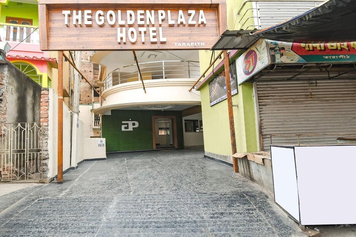 The entrance to The Golden Plaza Hotel with a sign above the door, a gated entrance, and a closed shop to the right.