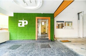 Una recepción con pared verde, puerta de madera y suelo de mármol.