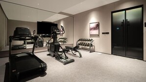 Un gimnasio moderno para el hogar con cinta de correr, elíptica y mancuernas.