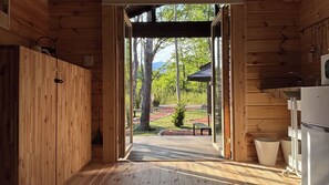 A wooden cabin interior with a view of a landscaped garden and a bench.