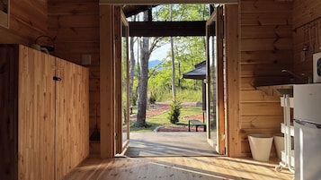 Innenansicht einer Holzhütte mit Blick auf einen angelegten Garten und einer Bank.
