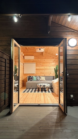 A wooden interior with a bed, pillows, and a small table.