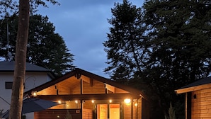 A wooden house with a covered porch, a gravel pathway, and a small garden. - mokku (Nasu)