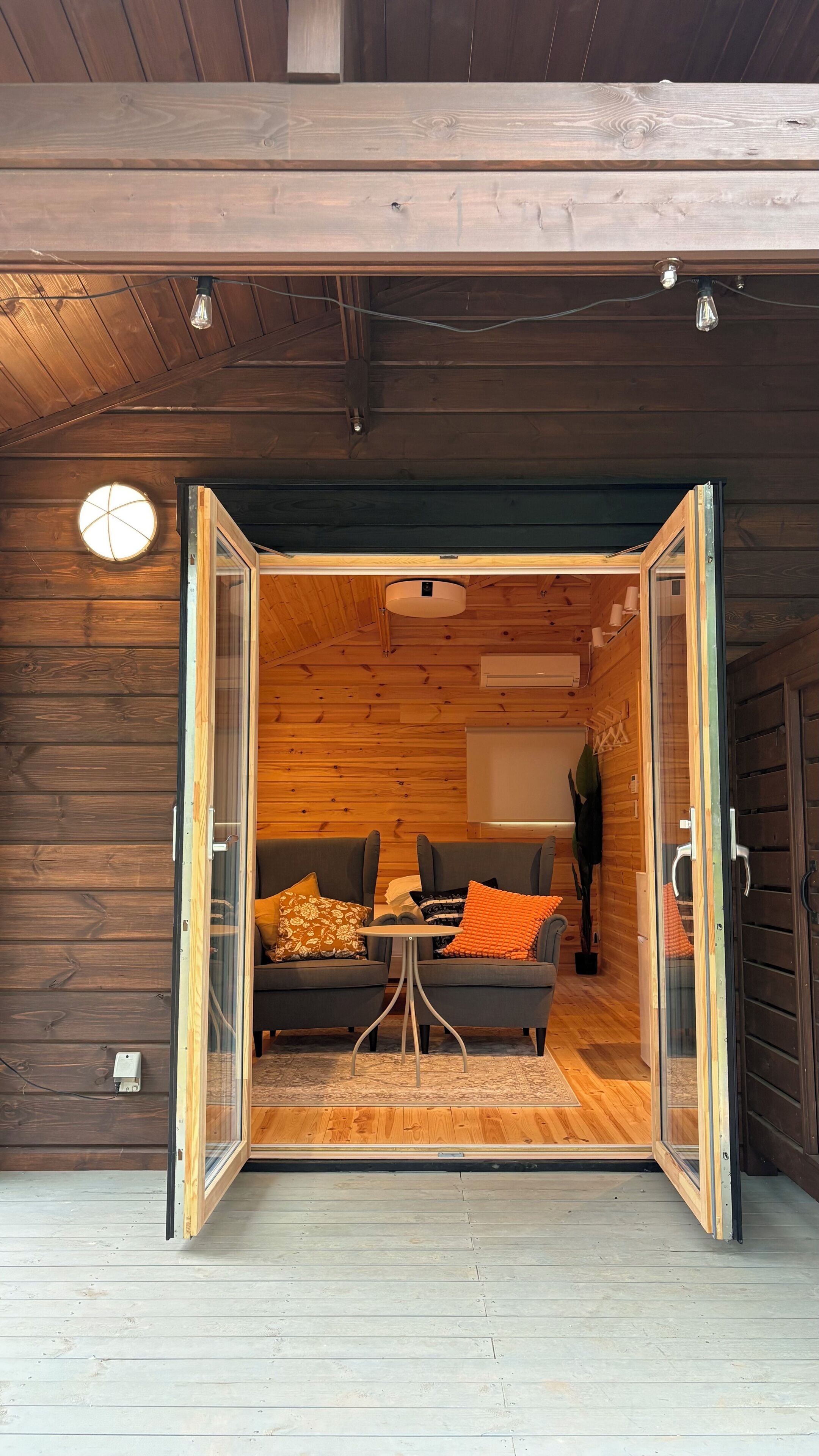 Eine offene Schiebetür führt in einen Raum mit zwei Sofas, einem kleinen Tisch und einem Fenster mit Blick.