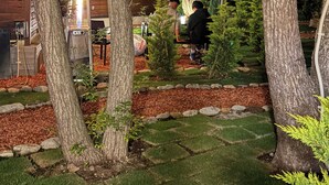 A nighttime view of a building with a visible heater, surrounded by trees and a well-maintained lawn.