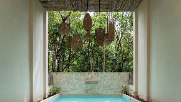 Ein Pool mit Steinmauer und hängenden Lampen.