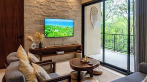 Ein modernes Wohnzimmer mit Steinwand, Flachbildfernseher, Sofa, Couchtisch und einem Balkon mit Blick.