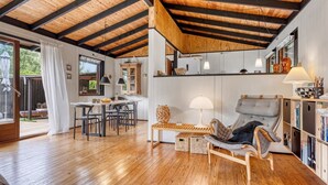 Uma sala de estar ampla com piso de madeira, uma mesa de jantar e um sofá.