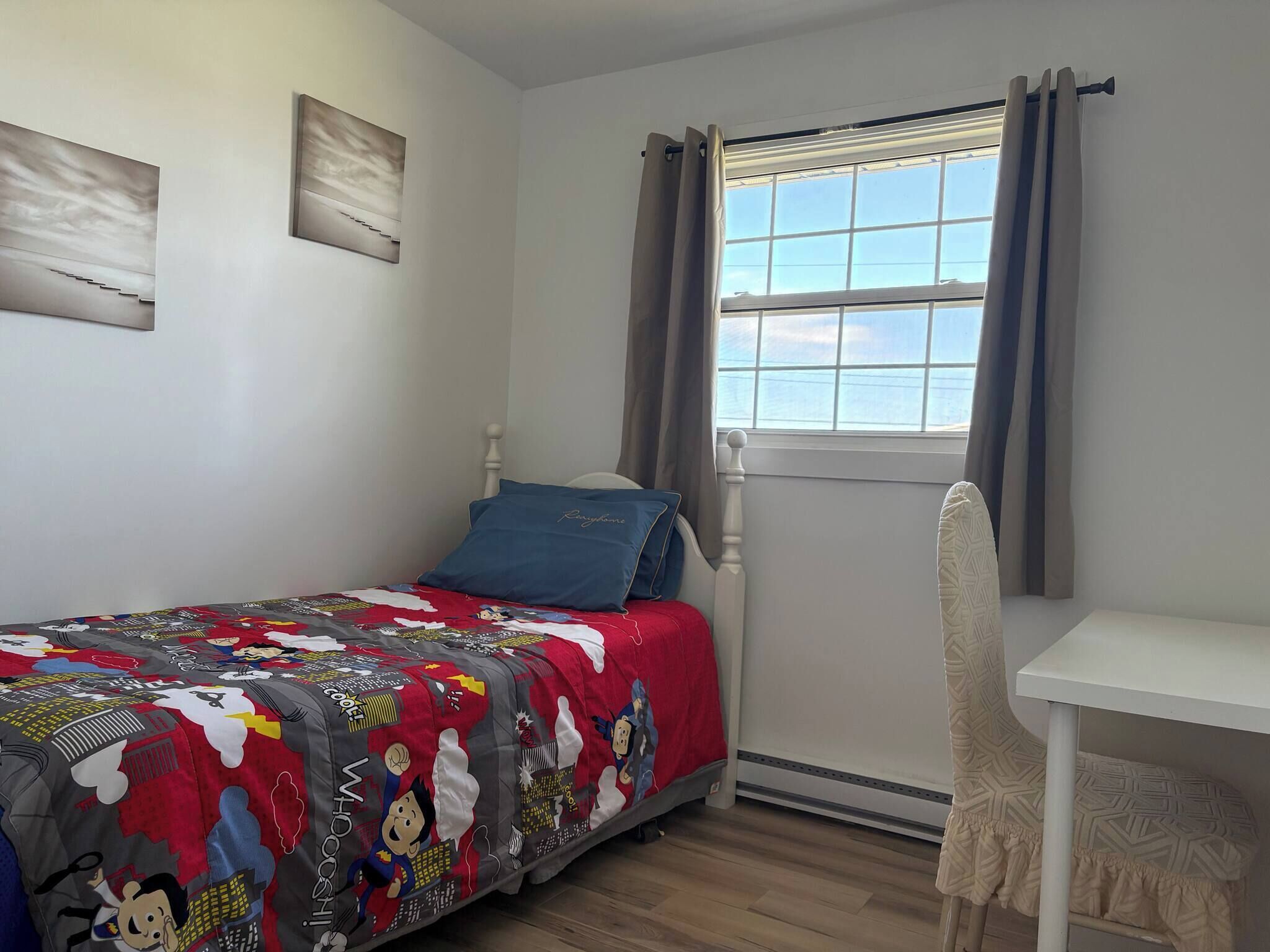 A bedroom with a bed, a window with curtains, a chair, and a desk.