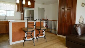 A kitchen with a central island, two bar stools, a refrigerator, and wooden cabinets.