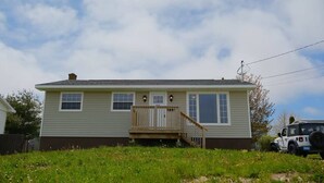 A single-story house with a front porch, a small deck, and a garage.