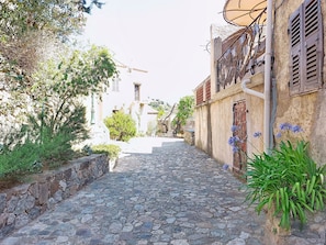 A narrow cobblestone street flanked by buildings with stone walls and shutters. - Casa Memmi Mouriès by Interhome (Palasca)