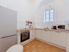 Eine kompakte Küche mit Kühlschrank, Backofen, Mikrowelle und einem Fenster über der Spüle.