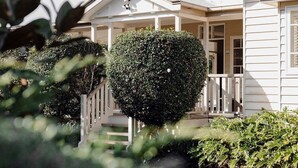 A house with a porch, a well-maintained hedge, and a staircase leading to the entrance.