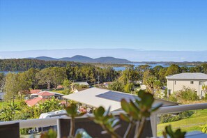 A residential area with houses, a solar panel on a building, and a view of a lake and mountains. - Large group retreat overlooking beautiful Wallis Lake with stunning views. (Coomba Park)