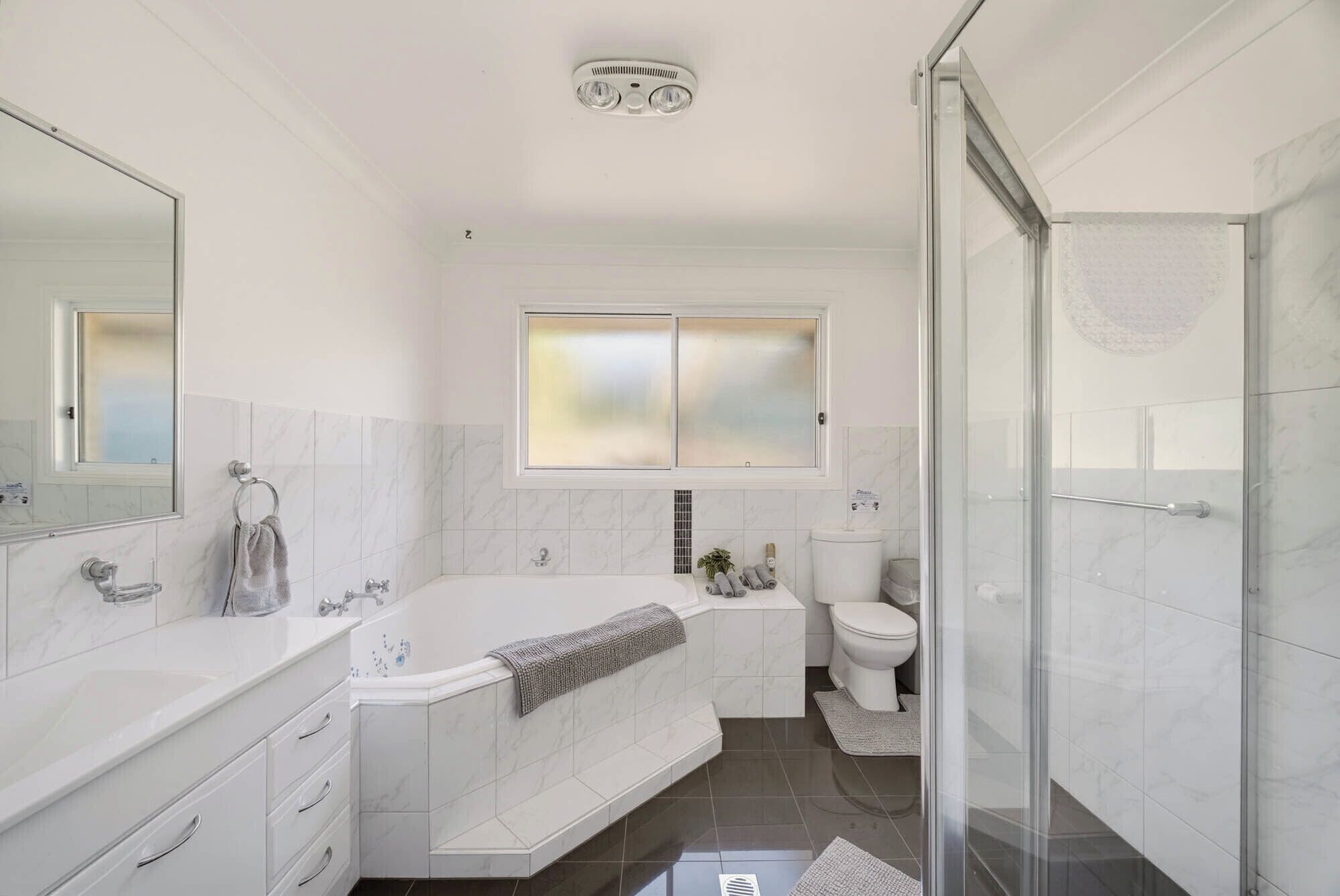 A modern bathroom with a bathtub, toilet, and shower area.