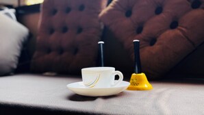 A white cup and saucer on a table with a yellow object beside it. - The Trikut Homestay – Just 1.4 km from Gadisar Lake (Jaisalmer)