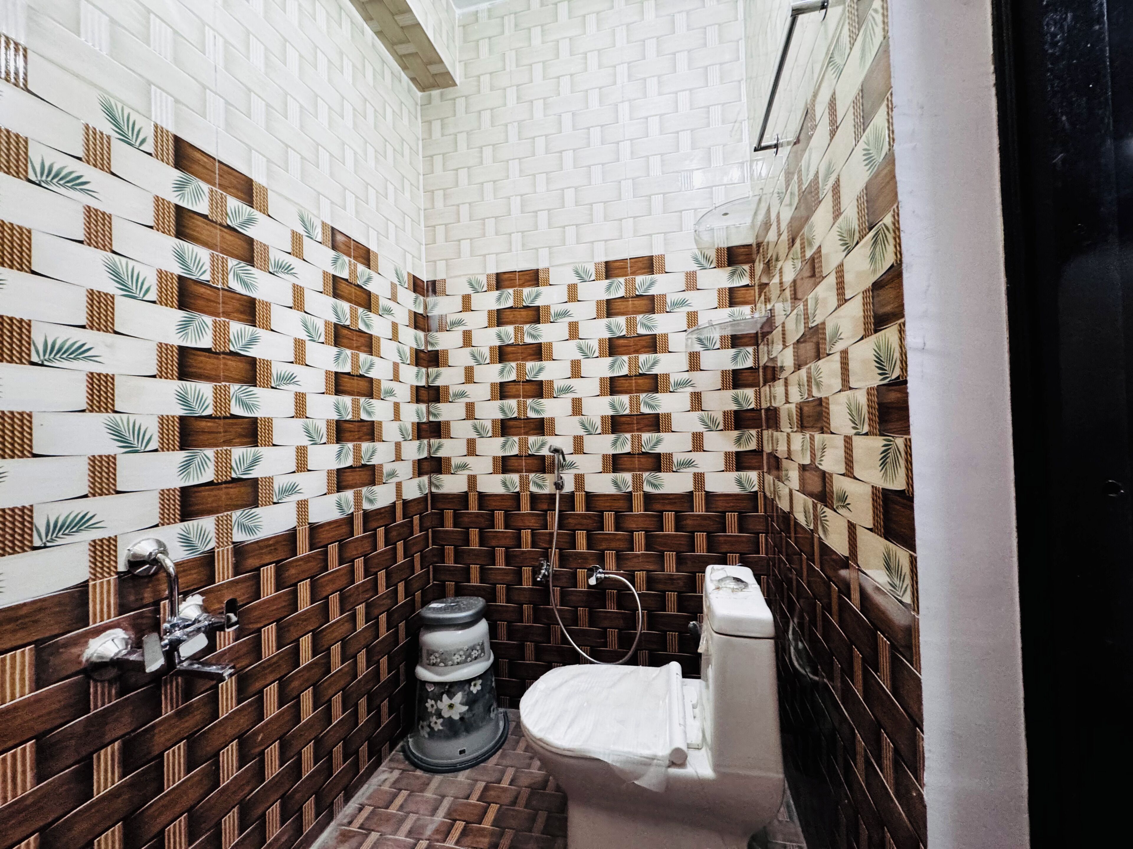 Et badeværelse med en væg af mønstret fliseværk, et toilet, en bidet og en vask.