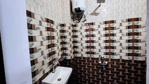 A bathroom with patterned tiles, a white sink, and a handheld showerhead. - The Trikut Homestay – Just 1.4 km from Gadisar Lake (Jaisalmer)