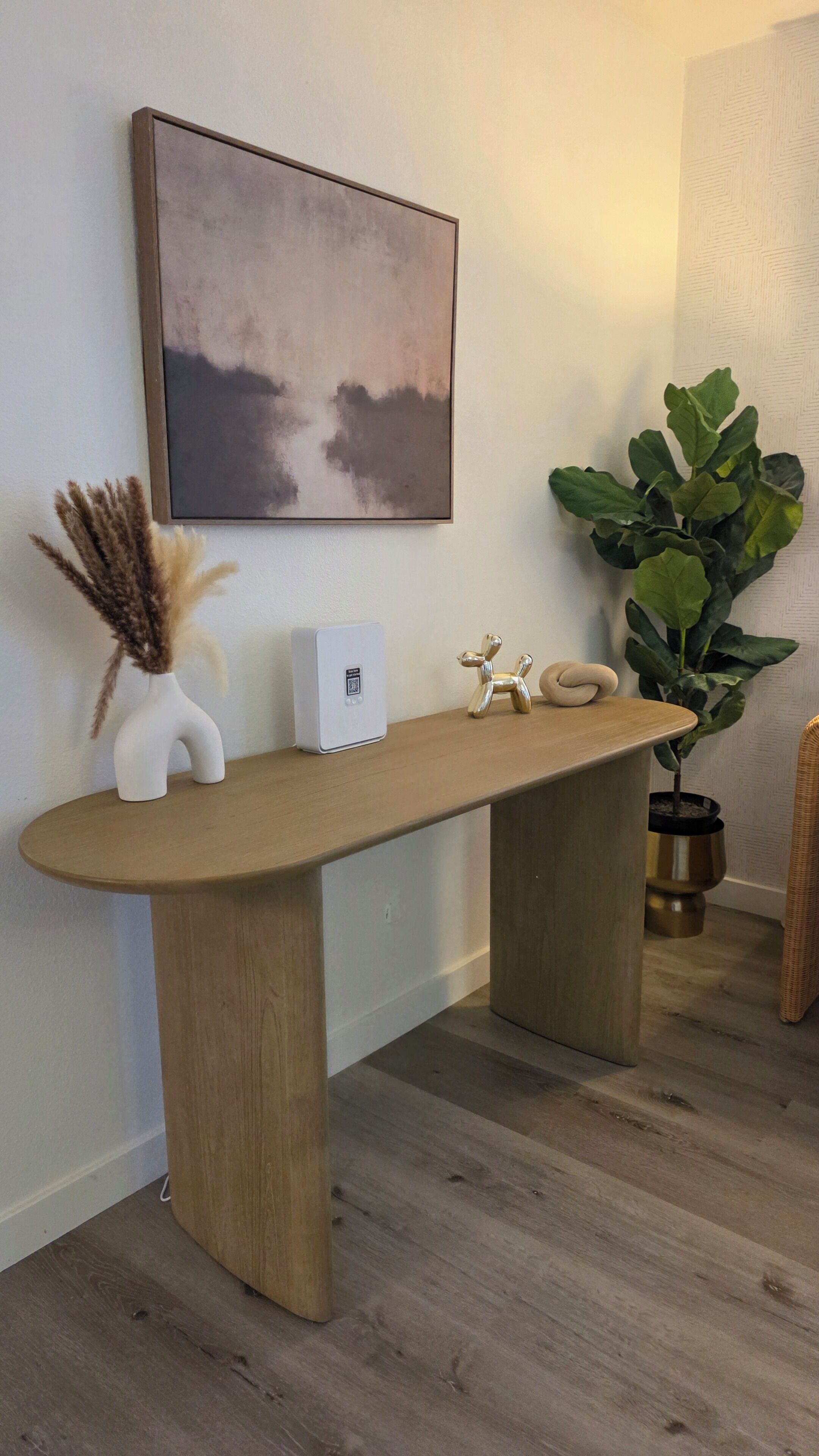 A wooden bench with a white vase and a small white device on it.