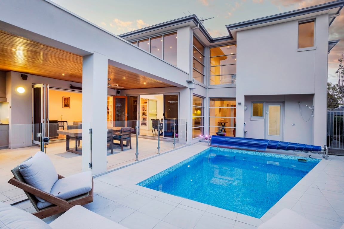 A modern residential property with a swimming pool, outdoor seating, and a covered patio area.