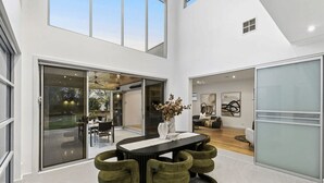 A modern interior with a dining area, a living space, and a view through a glass door. - The Anchorage on Henley (Charles Sturt)