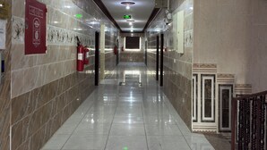 A corridor with marble walls, a polished floor, and a ceiling with recessed lighting.