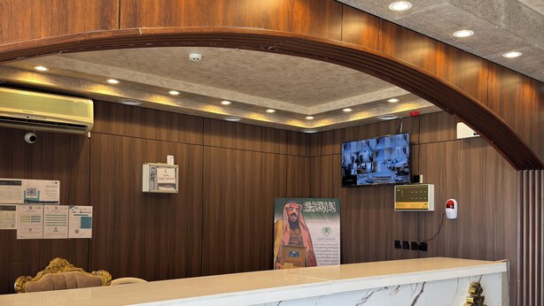 A reception desk with a marble top, wooden paneling, and a mounted television.