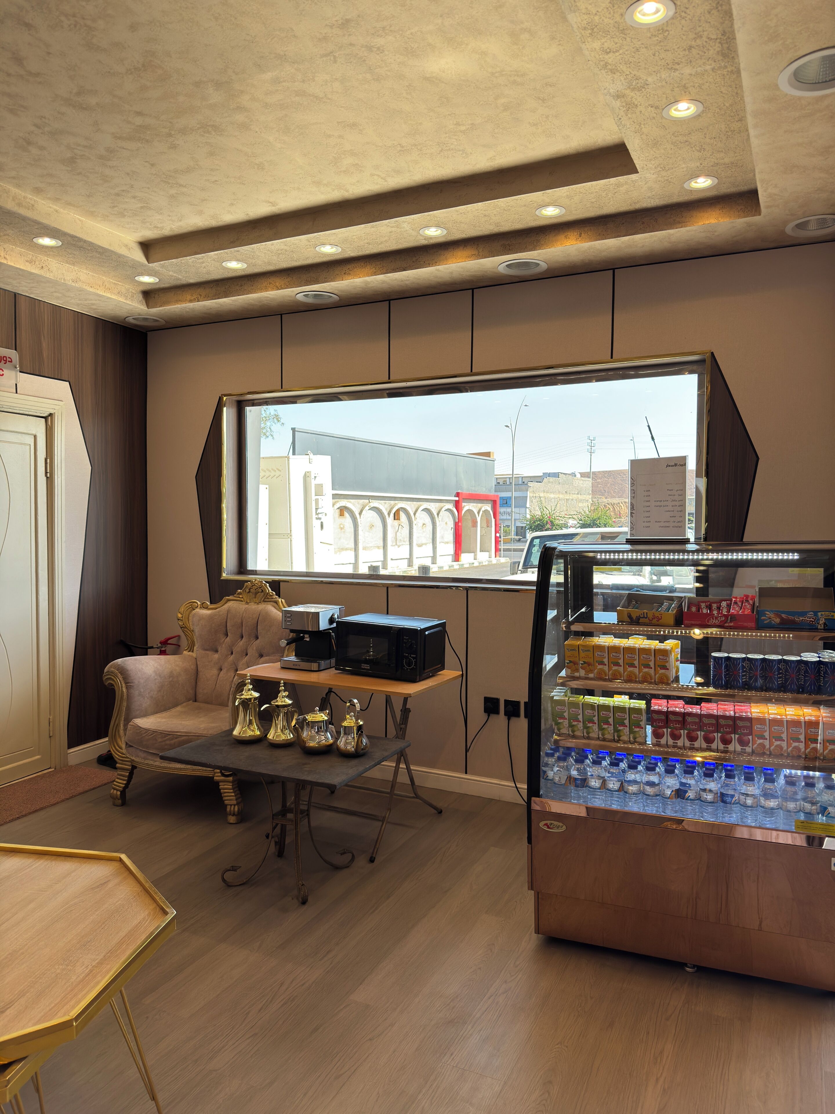 L’intérieur d’un café, avec un espace salon, une machine à café, un four à micro-ondes et un présentoir de boissons.