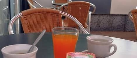 Una escena de desayuno con un plato de comida, un vaso de jugo de naranja, una taza de café y un croissant.