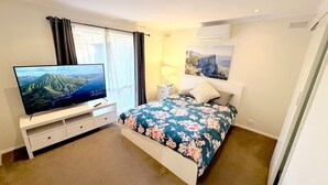 A bedroom with a bed, TV, and a window with curtains.