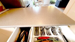 A kitchen drawer with utensils and a countertop.