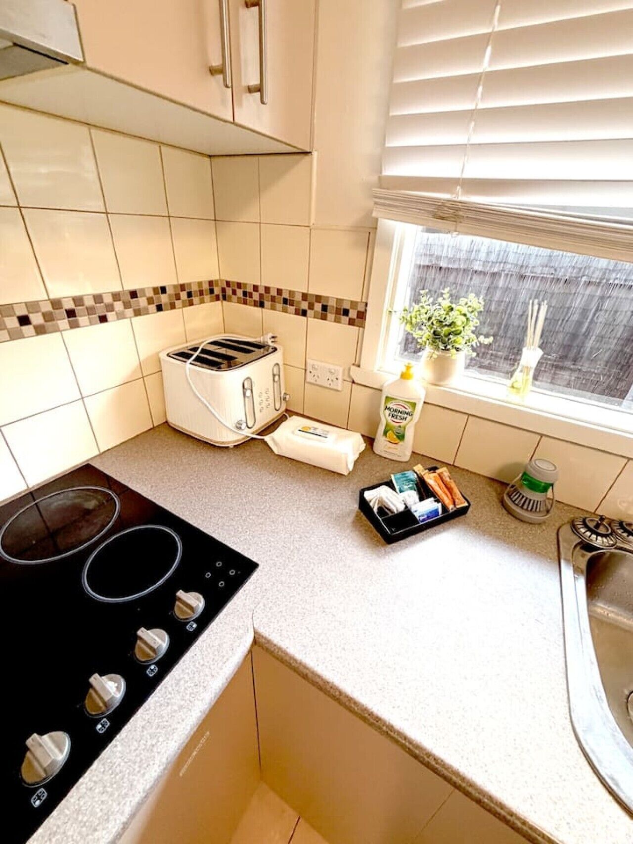 A compact kitchen with a gas stove, a toaster, and a window with a plant.