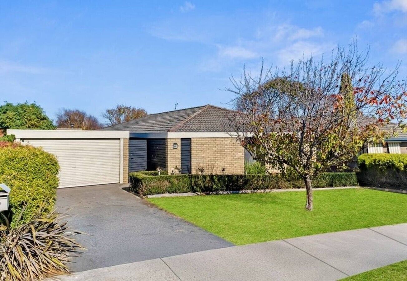 Ein Wohnhaus mit Garage, einem gepflegten Rasen und einem Baum im Vorgarten.